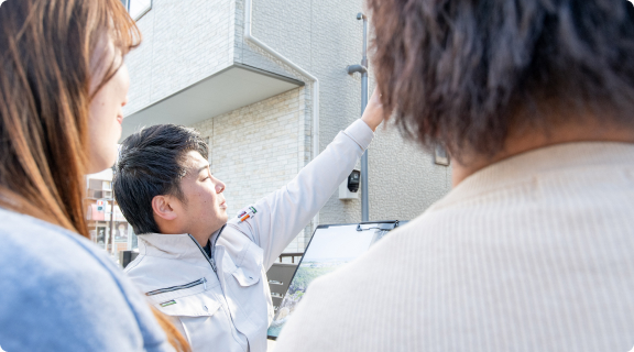 お客様宅で外壁の状態をご説明する担当スタッフ
