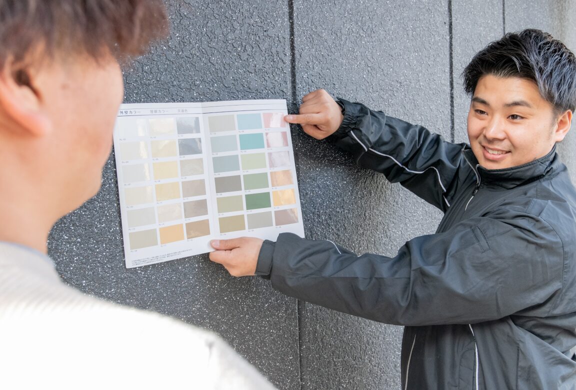 スタッフが外壁にサンプルを当ててお客様へ説明している